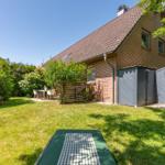 Hinterhof mit Garten, Tisch, Gartenmöbel und Terrasse. Haus mit Ziegeldach und Garagen.