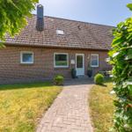 Ein Einfamilienhaus mit Backsteinfassade und Schieferdach. Ein gepflasterter Weg führt zur Eingangstür.