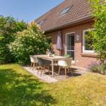 Hinterhof mit Sitzgruppe, Grill und Gartenhaus neben rotem Backsteinhaus.