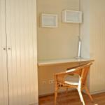 Work desk with chair and wall shelves. Wooden floor and wardrobe wall.