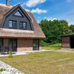 Haus mit Strohdach, Terrasse und Garten. Nebenhaus mit Holzkonstruktion.