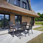 Terrasse mit Tisch und Stühlen vor einem Haus mit Dach und Fenstern.