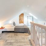 Bedroom with sloped ceiling, bed, nightstand, and clothing rack.