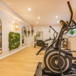 Fitnessraum mit Laufband, Spiegeln und Pflanzenwänden.