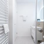 Badezimmer mit Dusche, Waschbecken und Heizkörper