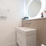 Badezimmer mit Waschbecken, Spiegel und Handtuchhalter.