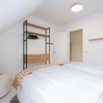 Schlafzimmer mit Doppelbett, Kleiderschrank und Sitzgelegenheit unter Dachschrägen.