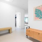 Flur mit Bank, Sideboard und Wandbild. Tür führt in Schlafzimmer.