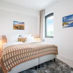 Schlafzimmer mit Bett, Wandbildern und Fenster.