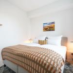 Schlafzimmer mit Bett, Wandbild und Nachttischlampen.