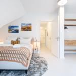 Schlafzimmer mit Dachschräge, Bett, Wandbildern und Kleiderschrank.
