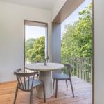 Terrasse mit runden Tisch und Stühlen, Blick auf grüne Bäume