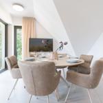Rundes Esszimmer mit sechs Stühlen und Blick auf Balkon.
