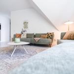 Wohnbereich mit Sofa, Couchtisch und Küchenzeile unter Dachschräge.