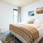 Schlafzimmer mit Doppelbett, Sessel und Fenster zur Terrasse.