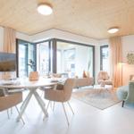 Wohn- und Essbereich mit Holzdecke, Glasfront und modernem Mobiliar.
