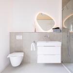 Badezimmer mit Dusche, Waschbecken und Toilette. Modernes Design mit beleuchtetem Spiegel.