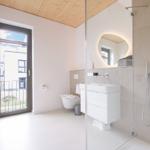 Badezimmer mit Dusche, Waschbecken und Toilette. Fenster mit Blick nach draußen.