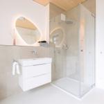 Moderne Badewanne mit Dusche, Waschbecken und Spiegel.