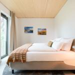 Schlafzimmer mit Bett, Fenster und Wandbildern.