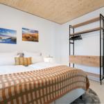 Schlafzimmer mit Bett, Kleiderständer und Wandbildern.