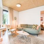 Wohnzimmer mit Sofa, Sessel und Tisch. Holzdecke und große Fenster.