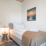 Ein Schlafzimmer mit Bett, Decke, Nachttisch und Wandbildern.