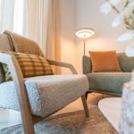 Ein Sessel mit Kissen und ein Sofa mit Kissen stehen im Raum.