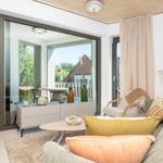 Wohnbereich mit Sofa, Couchtisch und Blick auf Balkon mit Tisch und Stühlen.