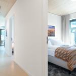 Schlafzimmer mit Bett, Fenster und Wandbild. Flur führt zum Essbereich.
