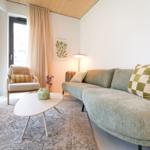 Ein Wohnzimmer mit Sofa, Sessel und Tisch. An der Wand hängt ein Bild.