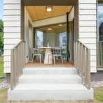 Haus mit Terrasse, Tisch und Stühlen. Holzdecke und Glaswände sichtbar.