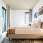 Schlafzimmer mit Bett, Wandbildern und Fenster zur Terrasse.