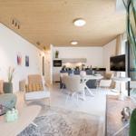 Wohn- und Essbereich mit Holzdecke, Sofa, Stuhl, Tisch und Fernseher.