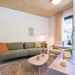 Wohnzimmer mit Sofa, Couchtisch und großem Fenster. Holzdecke und Wandbild sichtbar.