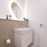 Badezimmer mit Waschbecken, Spiegel und Toilettenpapierhalter