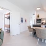 Wohn- und Essbereich mit Küchenzeile und Schlafzimmer im Hintergrund.