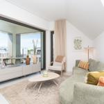 Wohnzimmer mit Sofa, Couchtisch und Blick auf Balkon.