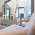 Wohnbereich mit Fernseher, Sideboard und Blick auf Balkon.