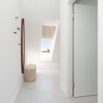 Flur mit Spiegel, Sitzbank und Dachfenster. Tür führt in einen Raum.