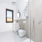 Moderne Dusche mit Glaswand, Waschbecken und Toilette. Fenster mit Jalousie.
