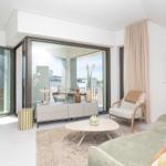Wohnzimmer mit Sofa, Sessel und Glasfront zur Terrasse.