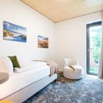 Schlafzimmer mit Bett, Sessel und Fenster zur Aussicht