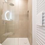Dusche mit Glaswand, Duschbrause und Heizung. Handtuch auf Heizung.