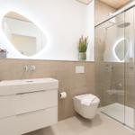 Badezimmer mit Dusche, Waschbecken und Toilette. Moderne Einrichtung und Beleuchtung.