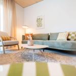Ein Wohnzimmer mit Sofa, Sessel, Tisch und Teppich.