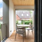 Terrasse mit runden Tisch und Stühlen, Holzboden und Blick auf Garten und Haus.