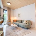 Wohnzimmer mit Sofa, Sessel und Tisch. Holzdecke und große Fenster.
