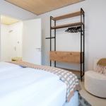 Schlafzimmer mit Bett, Kleiderschrank und Sessel. Holzdecke und weiße Wände.