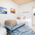 Ein Schlafzimmer mit Bett, Teppich und Wandbildern. Holzdecke und modernes Mobiliar.